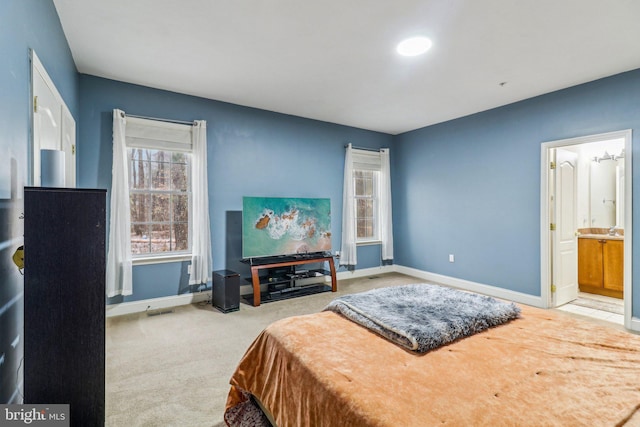 carpeted bedroom featuring visible vents, baseboards, and ensuite bathroom