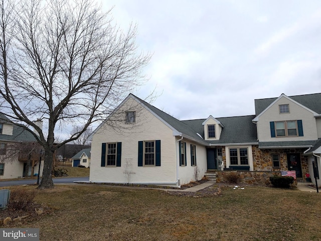 traditional-style home featuring stone siding and a front lawn