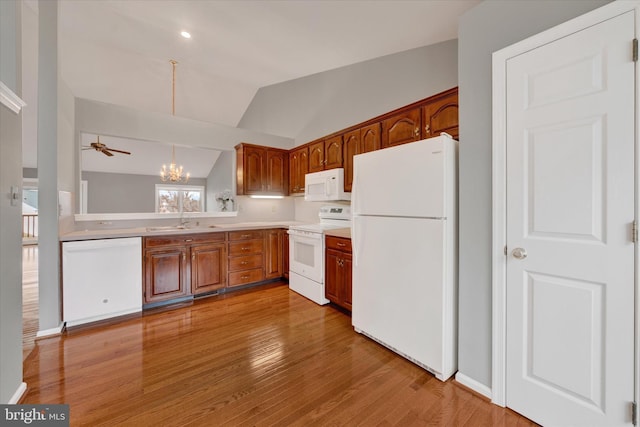 kitchen with white appliances, vaulted ceiling, light countertops, and brown cabinetry