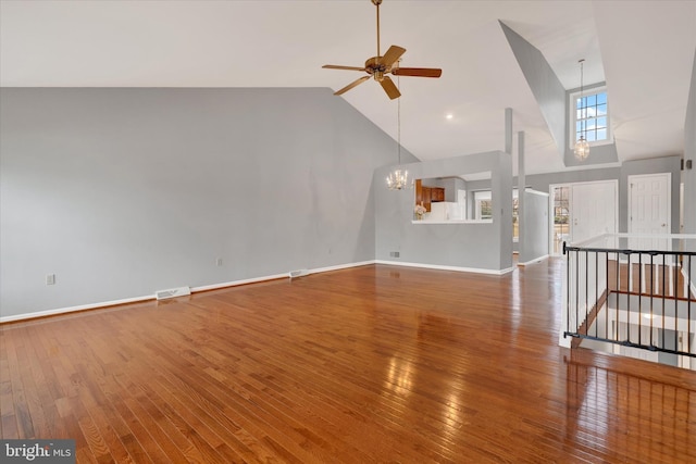 unfurnished living room with high vaulted ceiling, wood finished floors, and visible vents