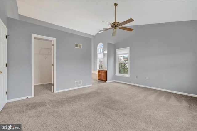 unfurnished bedroom with baseboards, a walk in closet, visible vents, and light colored carpet