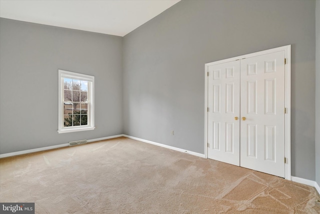 unfurnished bedroom featuring light carpet, baseboards, visible vents, and a closet