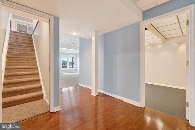 interior space with a paneled ceiling, baseboards, and wood finished floors