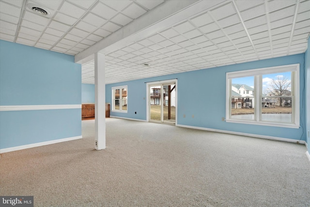 carpeted empty room with baseboards and a drop ceiling