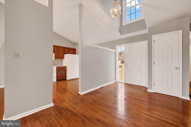 entrance foyer with a high ceiling, an inviting chandelier, wood finished floors, and baseboards