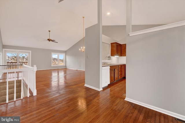 unfurnished living room with visible vents, baseboards, wood finished floors, high vaulted ceiling, and ceiling fan with notable chandelier