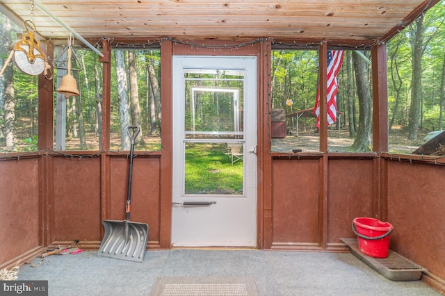 doorway to outside featuring carpet flooring and wood ceiling