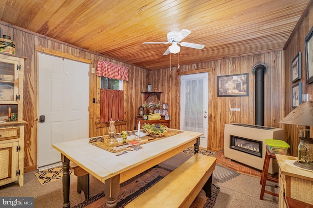 carpeted dining room featuring heating unit, a wood stove, wooden ceiling, and wooden walls