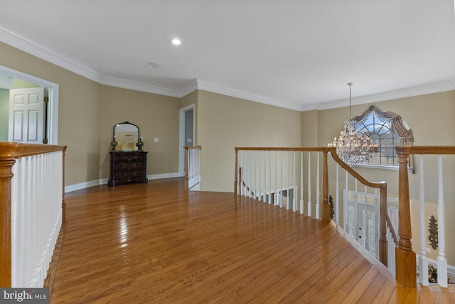 hallway with crown molding, wood-type flooring, and a notable chandelier