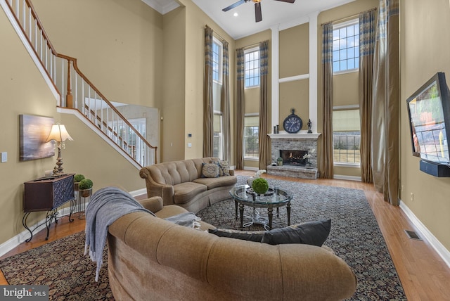 living room with a towering ceiling, ceiling fan, and light wood-type flooring