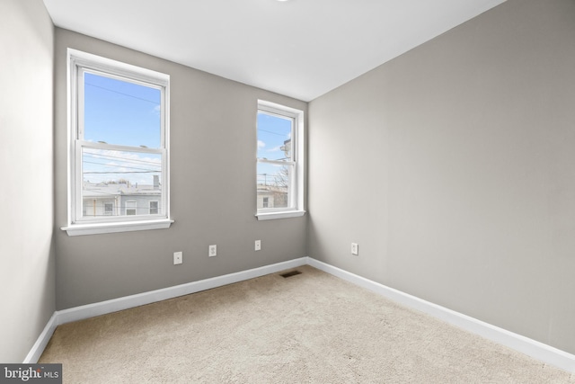 empty room featuring carpet floors, visible vents, and baseboards