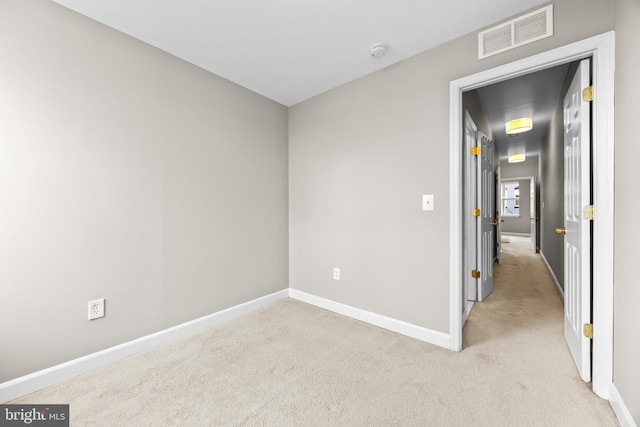 empty room with light colored carpet, visible vents, and baseboards