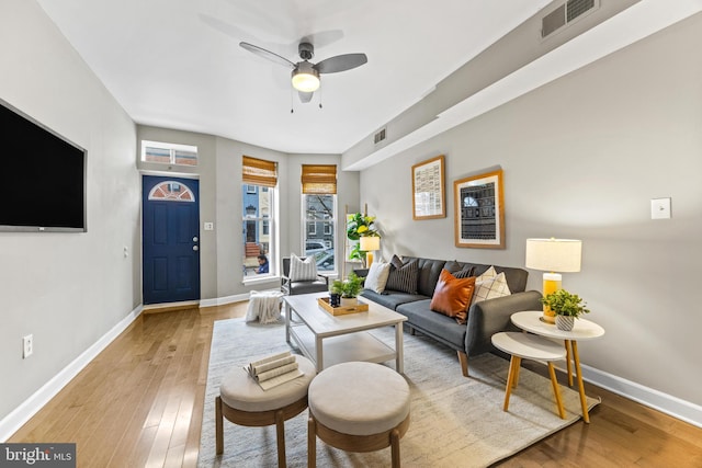 living area with a ceiling fan, light wood-type flooring, visible vents, and baseboards