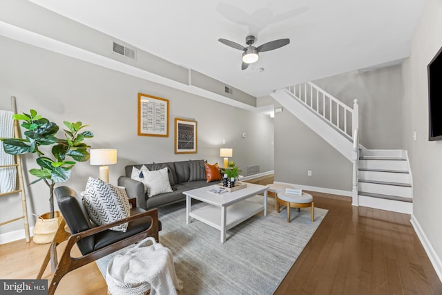 living area featuring a ceiling fan, stairs, visible vents, and wood finished floors