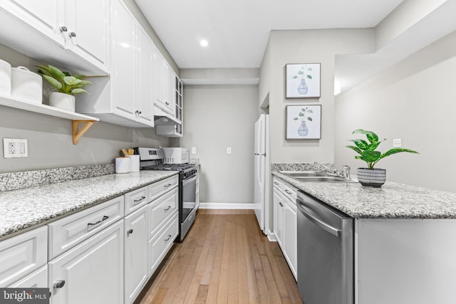 kitchen featuring appliances with stainless steel finishes, white cabinets, a sink, and light stone counters