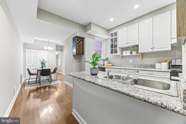 kitchen with light stone counters, glass insert cabinets, white cabinets, and a sink