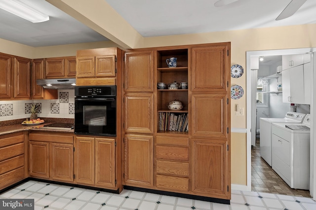 kitchen featuring open shelves, dark countertops, washer and dryer, under cabinet range hood, and black appliances