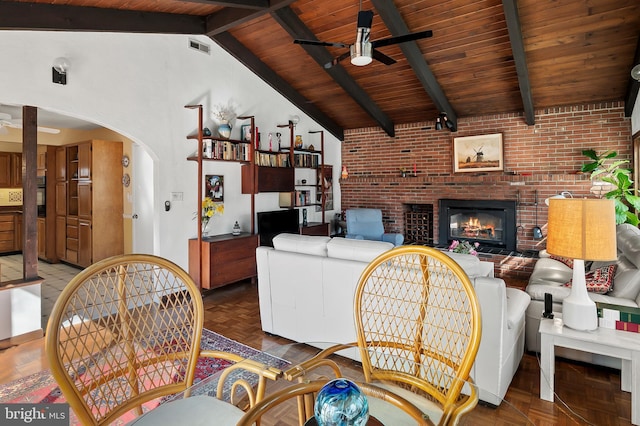 living room featuring arched walkways, a fireplace, visible vents, a ceiling fan, and beam ceiling