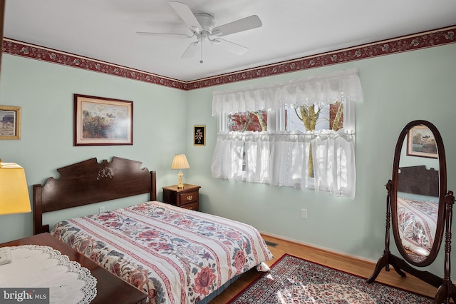 bedroom with a ceiling fan, baseboards, and wood finished floors