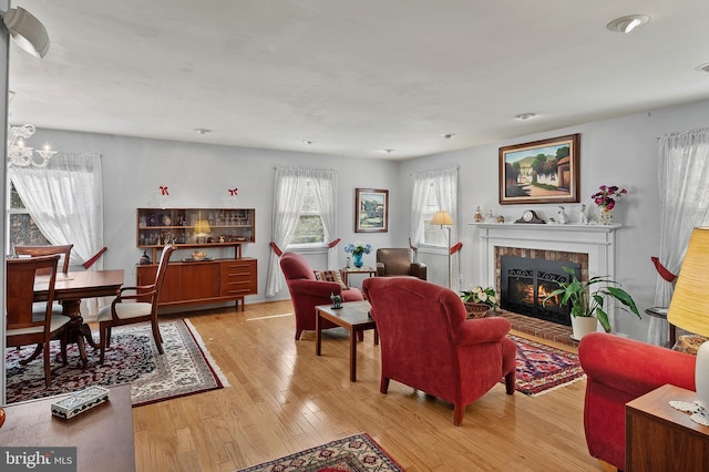 living room with a fireplace, an inviting chandelier, and light wood-style floors