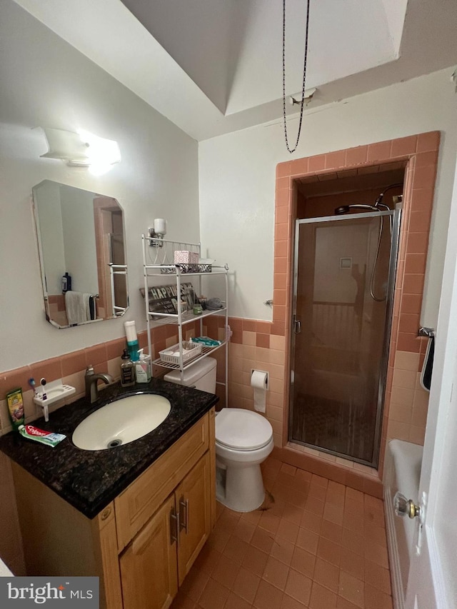 bathroom featuring vanity, toilet, an enclosed shower, and tile walls