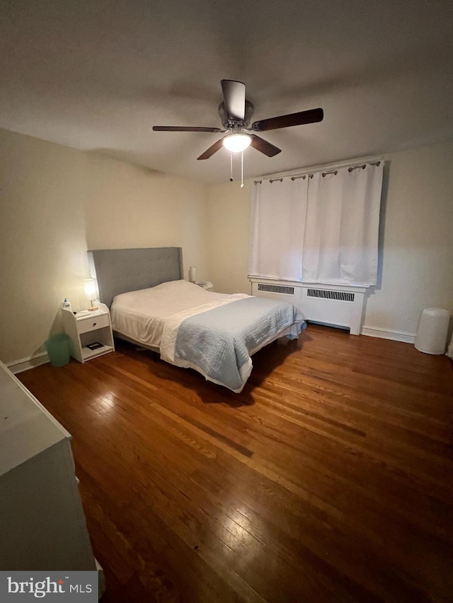 bedroom featuring radiator heating unit, dark hardwood / wood-style floors, and ceiling fan