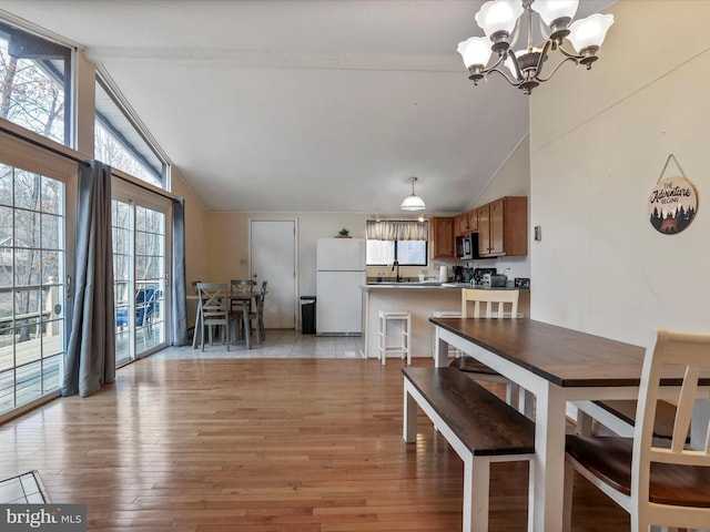 dining area featuring high vaulted ceiling, a notable chandelier, and light wood finished floors