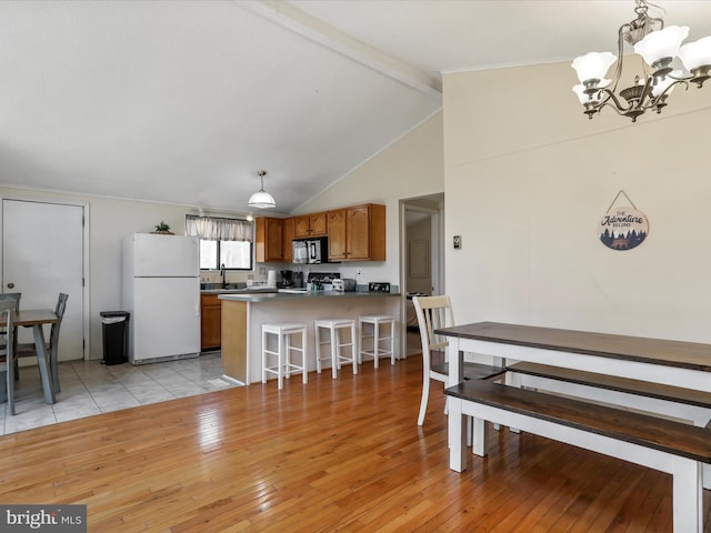 dining room with a notable chandelier, lofted ceiling with beams, and light wood-style floors