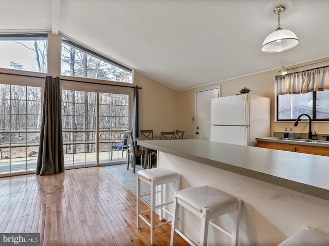 kitchen featuring vaulted ceiling with beams, wood finished floors, a sink, and freestanding refrigerator