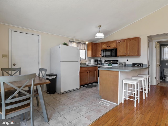 kitchen with brown cabinetry, electric stove, freestanding refrigerator, a peninsula, and black microwave