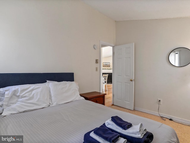 bedroom featuring lofted ceiling, light carpet, and baseboards