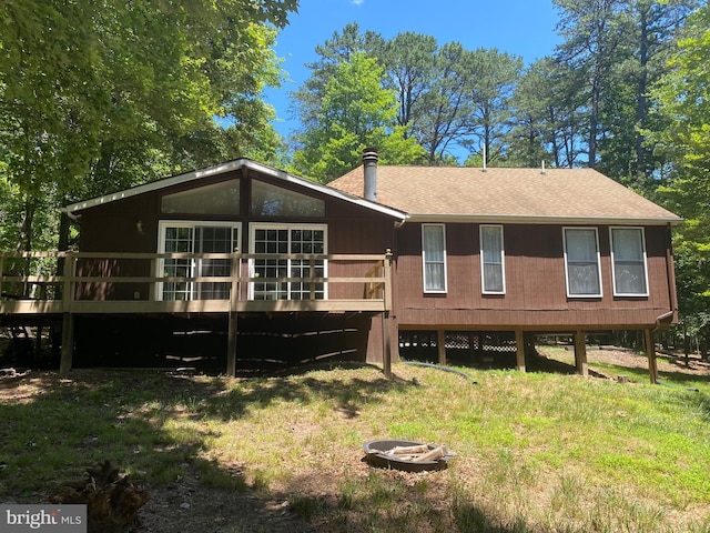 rear view of property with a wooden deck and roof with shingles