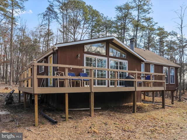 rear view of house featuring a deck and roof with shingles