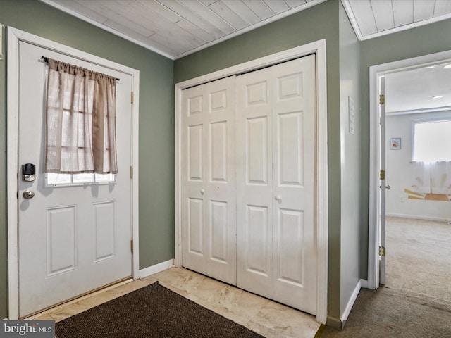 foyer entrance featuring ornamental molding, wooden ceiling, carpet flooring, and baseboards