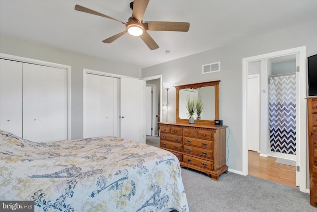 carpeted bedroom featuring ceiling fan and two closets