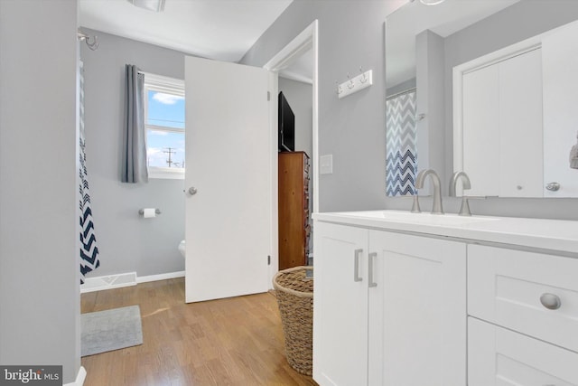 bathroom with hardwood / wood-style flooring, toilet, and vanity