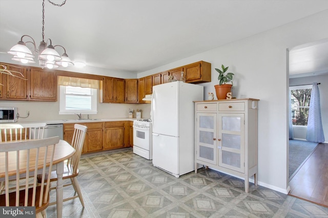 kitchen with appliances with stainless steel finishes, sink, pendant lighting, and a chandelier