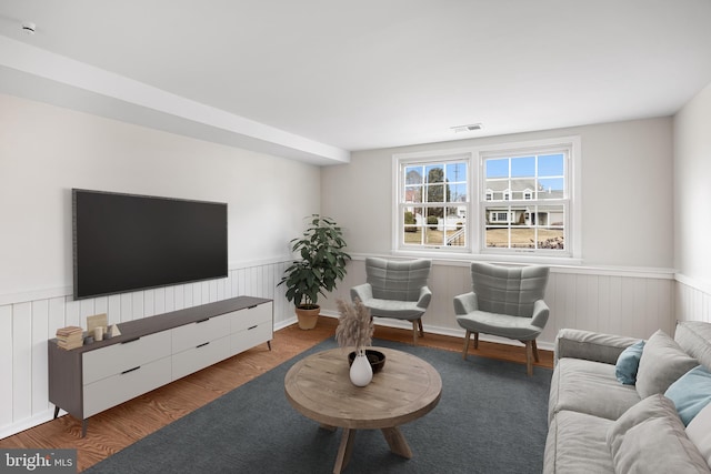 living room with a wainscoted wall, wood finished floors, and visible vents