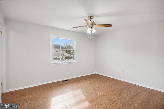 unfurnished room with a ceiling fan, visible vents, baseboards, and wood finished floors