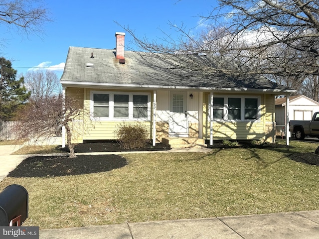 view of front of house featuring a shingled roof, a chimney, and a front lawn