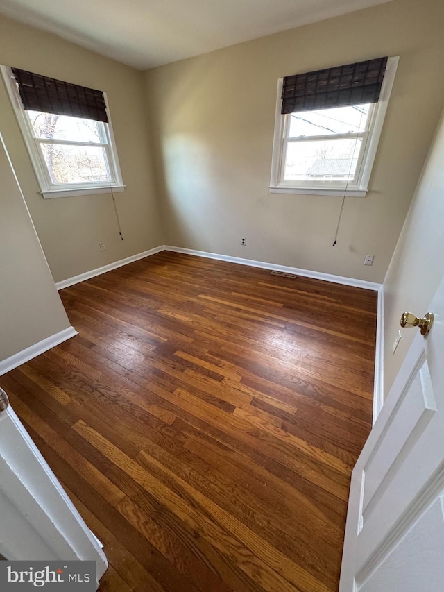 unfurnished room with baseboards and wood finished floors