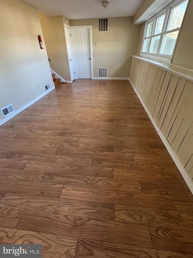 empty room featuring stairway, visible vents, and wood finished floors