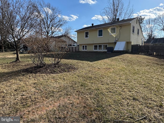 rear view of property with fence, cooling unit, and a yard