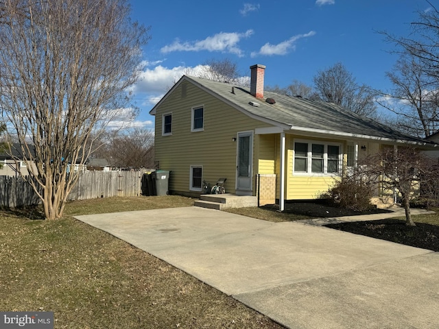 rear view of property featuring roof with shingles, a chimney, and fence