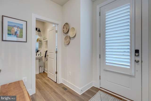 doorway with visible vents, light wood-style flooring, and baseboards