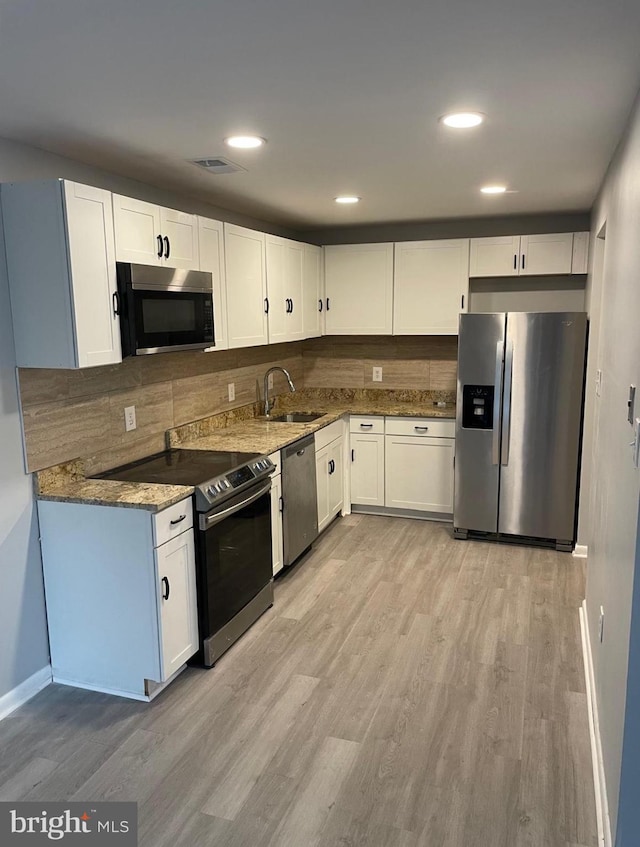 kitchen with stainless steel appliances, a sink, visible vents, white cabinets, and dark stone counters