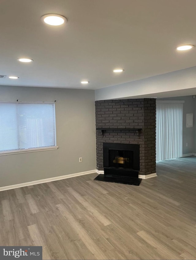 unfurnished living room with a brick fireplace and wood-type flooring