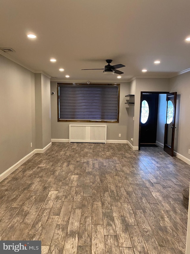 unfurnished living room with dark hardwood / wood-style flooring, crown molding, and radiator heating unit