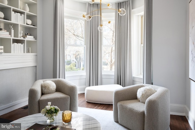 living area featuring a notable chandelier, wood finished floors, and baseboards