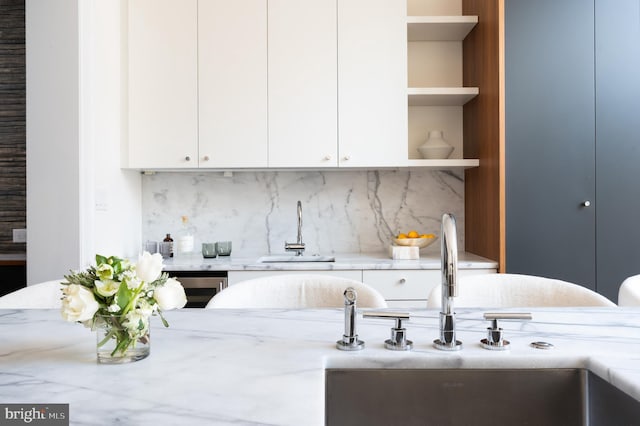 kitchen with open shelves, light stone countertops, tasteful backsplash, and a sink